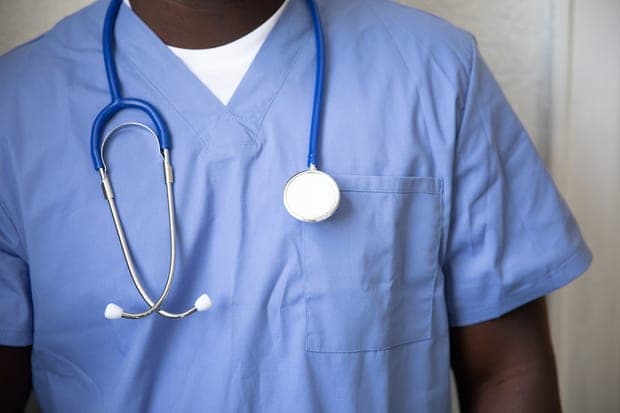 Un soignant en tunique bleue, stéthoscope autour du cou.